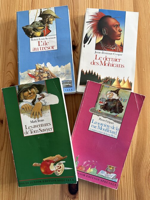 Quatre livres de poche : Les aventures de Tom Sawyer, La sorcière de la rue Mouffetard, L'île au trésor et Le dernier des Mohicans.